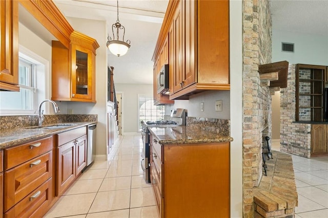 4000 Kawanee Ave, Metairie, LA 70002 - kitchen with appliances with stainless steel finishes, light tile patterned flooring, dark stone counters, glass insert cabinets, and hanging light fixtures