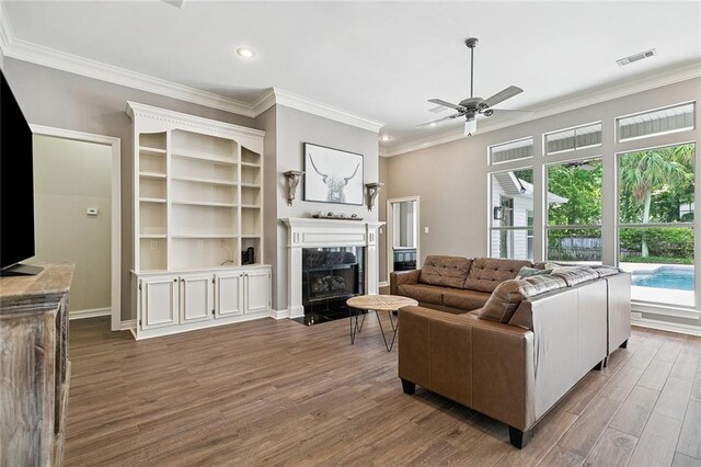 230 Delta Dr, Mandeville, LA 70448 - living room with healthy amount of natural light, wood finished floors, crown molding, ceiling fan, and a fireplace with flush hearth