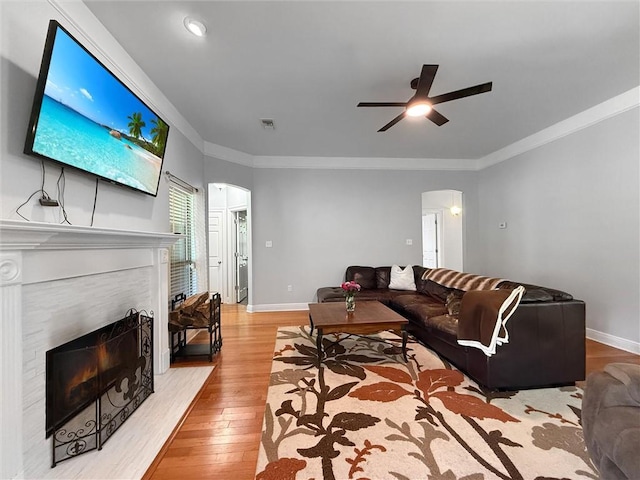 201 Stephanie Ln, Covington, LA 70435 - living room featuring arched walkways, a lit fireplace, light wood-style floors, a ceiling fan, and ornamental molding