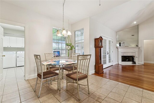 178 Colony Rd, Belle Chasse, LA 70037 - dining room featuring light tile patterned flooring, washing machine and dryer, a chandelier, vaulted ceiling, and a fireplace