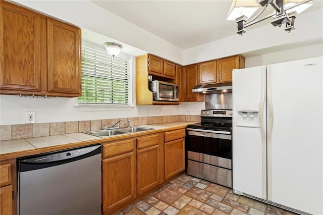 205 Timber Ridge Dr, Slidell, LA 70460 - kitchen with appliances with stainless steel finishes, under cabinet range hood, brown cabinetry, and tile counters