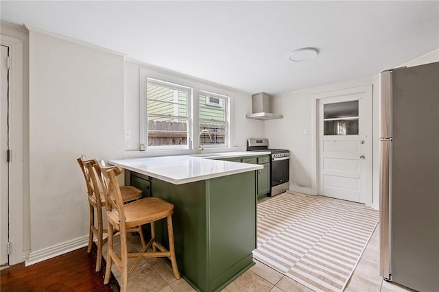 5624-5626 Annunciation St, New Orleans, LA 70115 - kitchen with stainless steel appliances, green cabinets, a peninsula, wall chimney range hood, and a kitchen bar