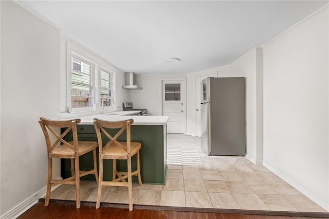5624-5626 Annunciation St, New Orleans, LA 70115 - kitchen featuring appliances with stainless steel finishes, a peninsula, wall chimney exhaust hood, crown molding, and a kitchen bar