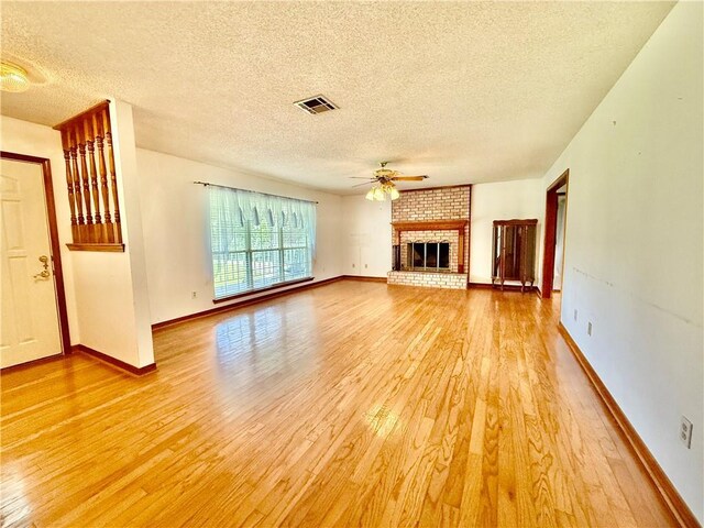 7282 Barataria Blvd, Marrero, LA 70072 - unfurnished living room with light wood finished floors, a textured ceiling, a ceiling fan, and a fireplace