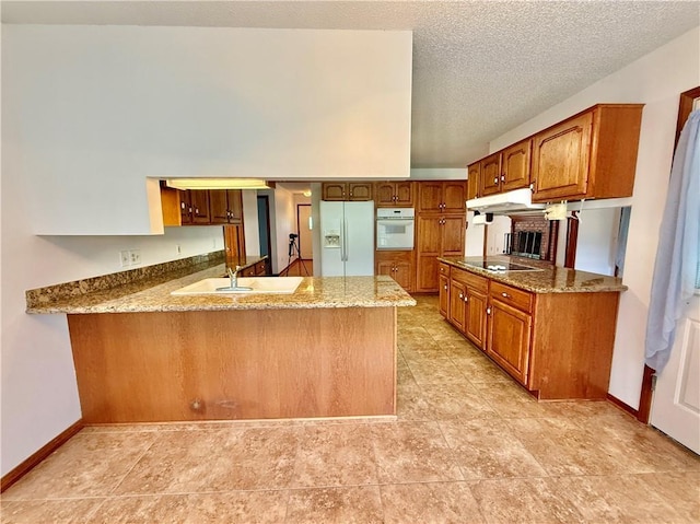 7282 Barataria Blvd, Marrero, LA 70072 - kitchen with white appliances, under cabinet range hood, a peninsula, brown cabinetry, and light stone countertops