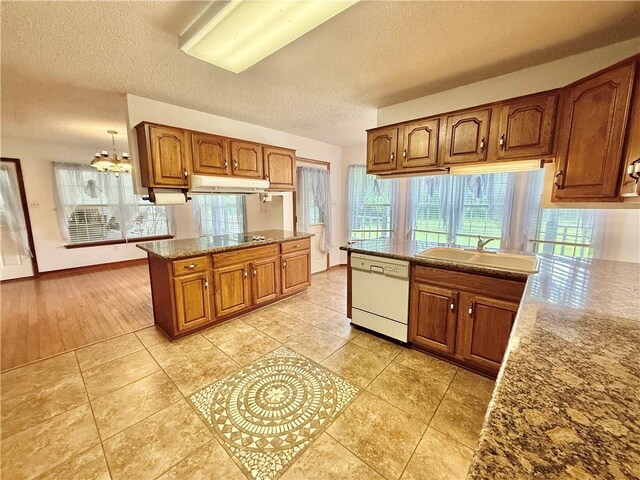 7282 Barataria Blvd, Marrero, LA 70072 - kitchen with dishwasher, under cabinet range hood, brown cabinets, a textured ceiling, and a peninsula