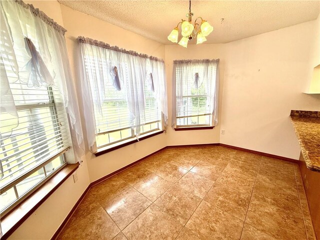 7282 Barataria Blvd, Marrero, LA 70072 - unfurnished dining area featuring a chandelier, a textured ceiling, and tile patterned flooring