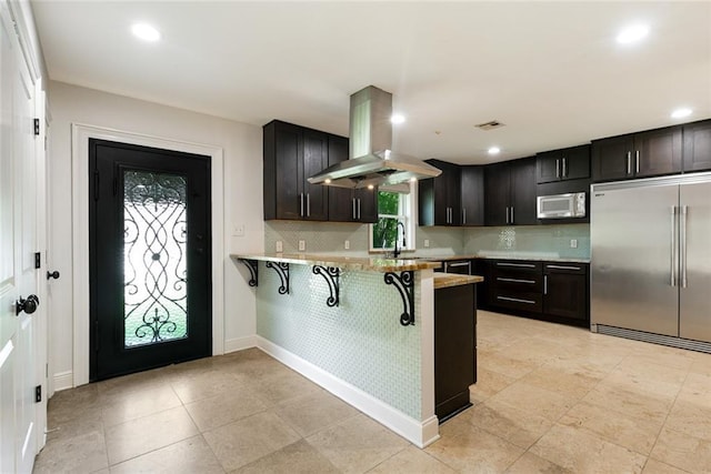 700 Crystal St, New Orleans, LA 70124 - kitchen featuring built in refrigerator, island exhaust hood, white microwave, a peninsula, and a breakfast bar