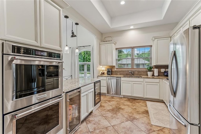 1580 Cherry Ridge Ct, Mandeville, LA 70448 - kitchen featuring appliances with stainless steel finishes, beverage cooler, light stone countertops, backsplash, and white cabinetry