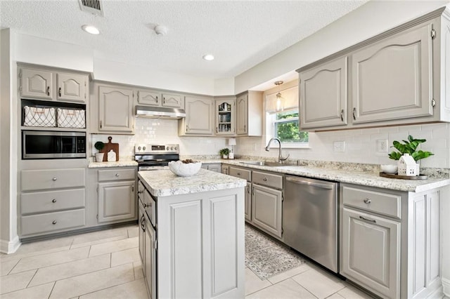 33 Rosedown Dr, Destrehan, LA 70047 - kitchen with appliances with stainless steel finishes, gray cabinets, under cabinet range hood, and a textured ceiling