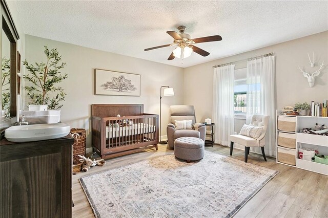 33 Rosedown Dr, Destrehan, LA 70047 - bedroom with light wood-type flooring, a crib, a textured ceiling, and a ceiling fan