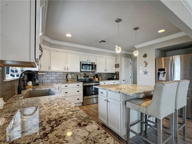 4230 Murano Rd, New Orleans, LA 70129 - kitchen with appliances with stainless steel finishes, a center island, crown molding, white cabinetry, and a breakfast bar