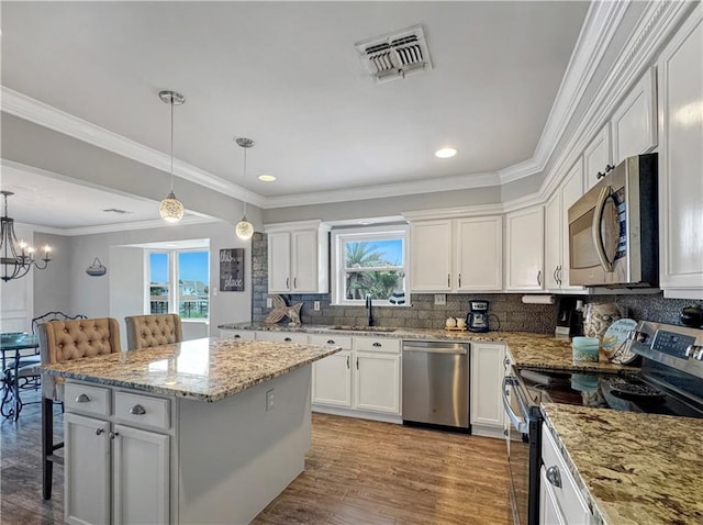 4230 Murano Rd, New Orleans, LA 70129 - kitchen with stainless steel appliances, a breakfast bar, a center island, white cabinetry, and recessed lighting