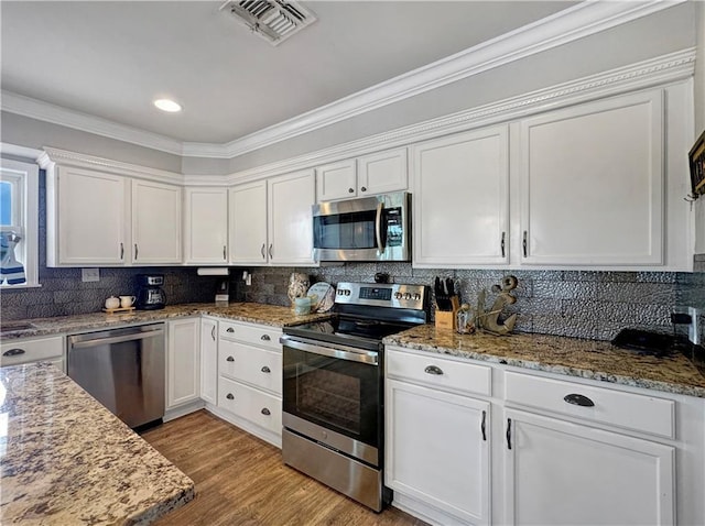 4230 Murano Rd, New Orleans, LA 70129 - kitchen featuring appliances with stainless steel finishes, white cabinetry, light stone counters, tasteful backsplash, and ornamental molding