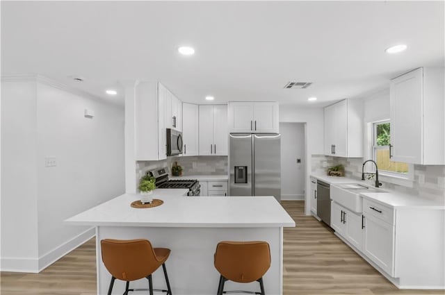 540 Ruth Dr, Westwego, LA 70094 - kitchen with appliances with stainless steel finishes, a kitchen bar, a peninsula, tasteful backsplash, and recessed lighting