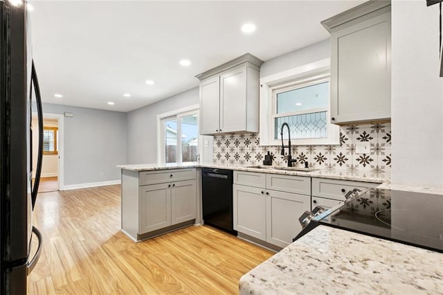7032 Glenn St, Metairie, LA 70003 - kitchen with black appliances, gray cabinetry, a peninsula, light wood finished floors, and tasteful backsplash