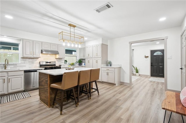 713 N Lester Ave, Metairie, LA 70003 - kitchen with stainless steel appliances, a breakfast bar area, a kitchen island, light countertops, and light wood finished floors