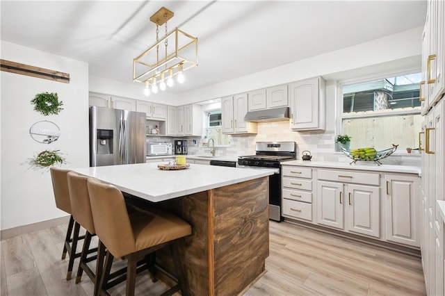 713 N Lester Ave, Metairie, LA 70003 - kitchen featuring stainless steel appliances, under cabinet range hood, tasteful backsplash, light countertops, and healthy amount of natural light