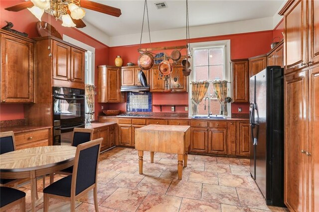 202 S Pierce St, New Orleans, LA 70119 - kitchen with black appliances, a ceiling fan, brown cabinets, and light stone finish floors