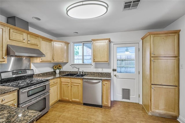 5538 Bellaire Dr, New Orleans, LA 70124 - kitchen featuring appliances with stainless steel finishes, range hood, light brown cabinetry, light wood-type flooring, and dark stone countertops