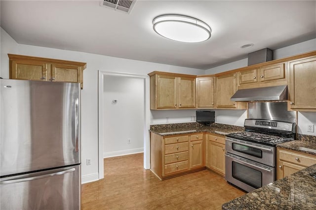 5538 Bellaire Dr, New Orleans, LA 70124 - kitchen with appliances with stainless steel finishes, wall chimney range hood, dark stone countertops, and light flooring