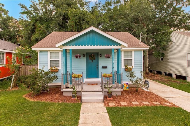 4108 Rayne Dr, New Orleans, LA 70122 - bungalow-style home with covered porch, roof with shingles, and a front lawn