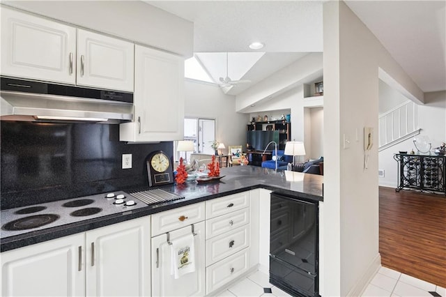 105 Mariners Is Unit 105, Mandeville, LA 70448 - kitchen featuring under cabinet range hood, white cooktop, light tile patterned floors, white cabinetry, and dark countertops