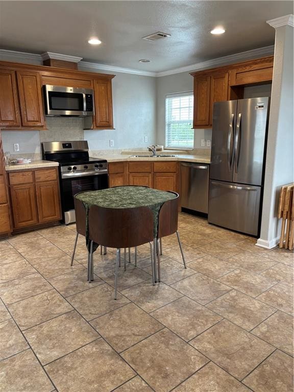 24092 Chef Menteur Hwy, New Orleans, LA 70129 - kitchen featuring appliances with stainless steel finishes, brown cabinetry, light countertops, ornamental molding, and recessed lighting