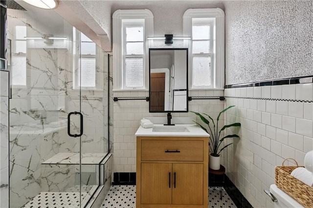 4752 Demontluzin St, New Orleans, LA 70122 - bathroom featuring tile walls, a marble finish shower, vanity, and a wainscoted wall