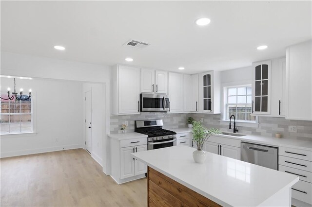 1909 Maryland Ave, Kenner, LA 70062 - kitchen with appliances with stainless steel finishes, glass insert cabinets, backsplash, light wood finished floors, and recessed lighting