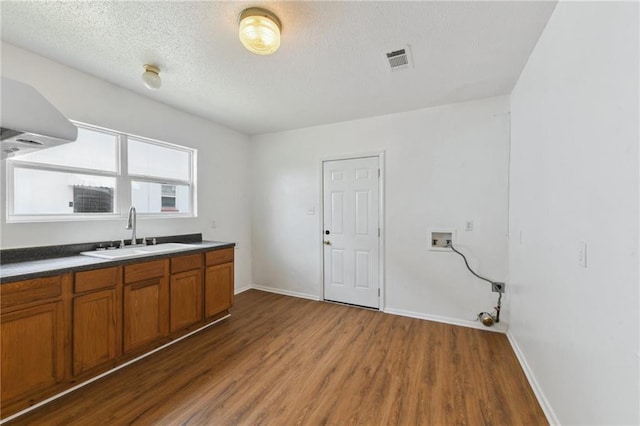4601 Reynes St, New Orleans, LA 70126 - kitchen with brown cabinetry, wood finished floors, a textured ceiling, and dark countertops