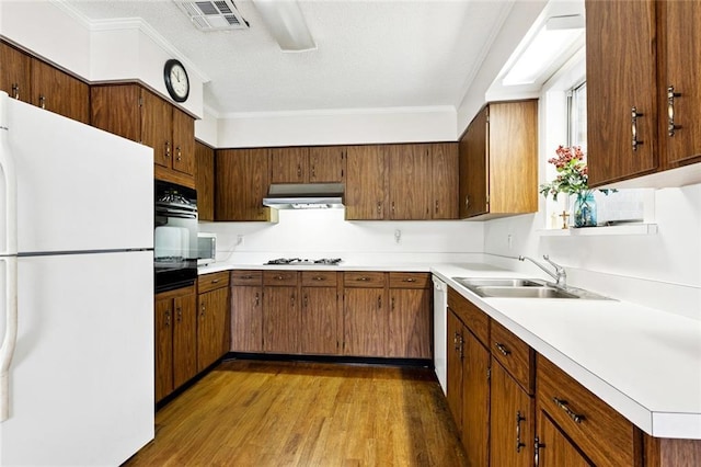 508 Beverly Garden Dr, Metairie, LA 70005 - kitchen featuring white appliances, under cabinet range hood, light countertops, wood finished floors, and crown molding
