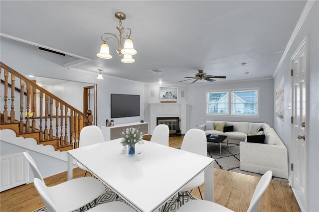174 Celia Dr, Luling, LA 70070 - dining area featuring light wood-style floors, ceiling fan, a glass covered fireplace, crown molding, and stairs