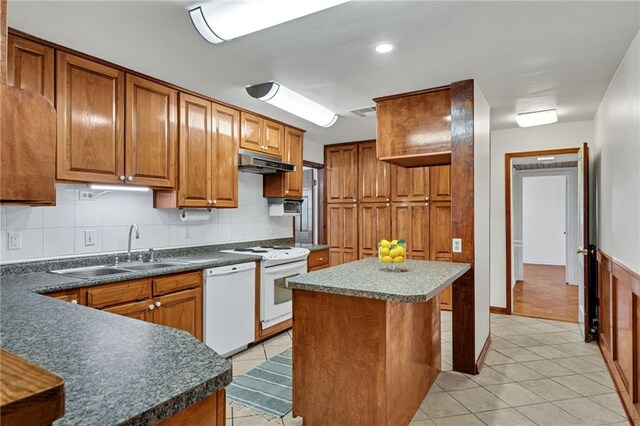 174 Celia Dr, Luling, LA 70070 - kitchen with white appliances, under cabinet range hood, light tile patterned floors, and brown cabinets