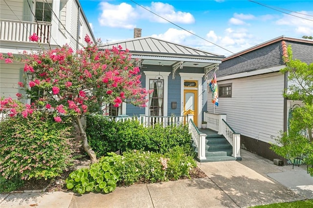 422 Alix St, New Orleans, LA 70114 - view of front facade featuring a standing seam roof, a chimney, a porch, and a metal roof