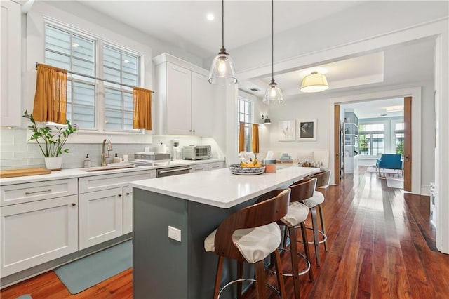 422 Alix St, New Orleans, LA 70114 - kitchen featuring a kitchen island, dark wood-style flooring, light countertops, white cabinetry, and a breakfast bar