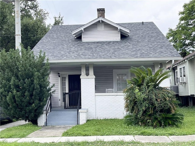 7935 Fig St, New Orleans, LA 70125 - bungalow-style house with roof with shingles, a chimney, brick siding, cooling unit, and covered porch