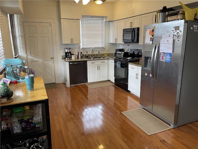 7935 Fig St, New Orleans, LA 70125 - kitchen with black appliances, white cabinets, wood finished floors, and dark stone countertops