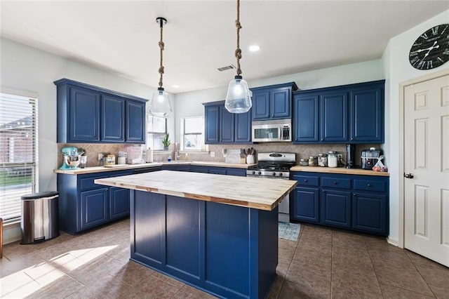 13795 Shady Hollow Dr, Denham Springs, LA 70726 - kitchen with butcher block countertops, blue cabinetry, stainless steel appliances, decorative backsplash, and recessed lighting