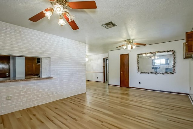 2219 Mercedes Blvd, New Orleans, LA 70114 - unfurnished living room featuring ceiling fan, a textured ceiling, wood finished floors, and brick wall