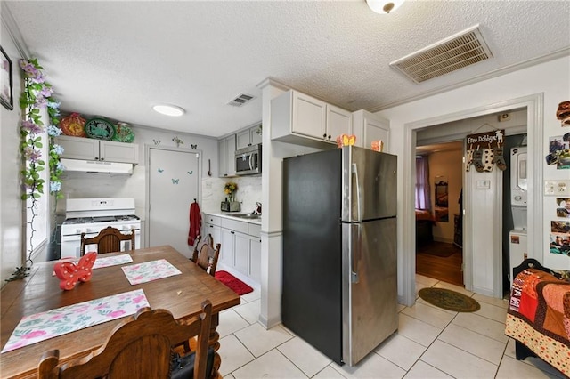 1500 Shirley Dr, New Orleans, LA 70114 - kitchen with appliances with stainless steel finishes, under cabinet range hood, a textured ceiling, light tile patterned flooring, and decorative backsplash