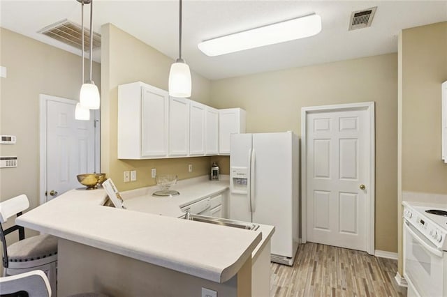 521 Spartan Dr Unit 10207, Slidell, LA 70458 - kitchen with white appliances, light wood-style floors, a breakfast bar area, a peninsula, and white cabinetry