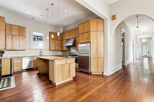 3354 Esplanade Ave, New Orleans, LA 70119 - kitchen featuring appliances with stainless steel finishes, wall chimney exhaust hood, dark wood finished floors, arched walkways, and light countertops