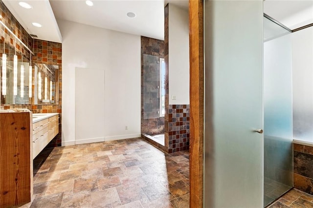 3354 Esplanade Ave, New Orleans, LA 70119 - full bathroom with vanity, stone tile flooring, a tile shower, recessed lighting, and tile walls