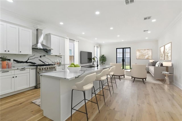 4542 Prairie St, Metairie, LA 70001 - kitchen with wall chimney range hood, high end stove, ornamental molding, decorative backsplash, and open floor plan