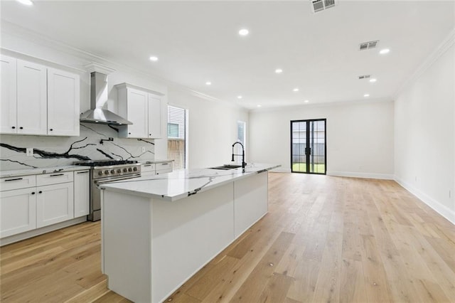 4542 Prairie St, Metairie, LA 70001 - kitchen with wall chimney exhaust hood, high end stainless steel range, crown molding, decorative backsplash, and white cabinetry