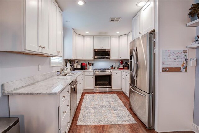 1112 Compromise St, Kenner, LA 70062 - kitchen featuring stainless steel appliances, wood finished floors, white cabinetry, light stone counters, and recessed lighting