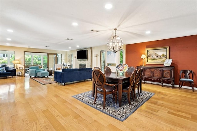 285 Oak Dr, Mandeville, LA 70471 - dining space with a chandelier, light wood-type flooring, a fireplace, and recessed lighting