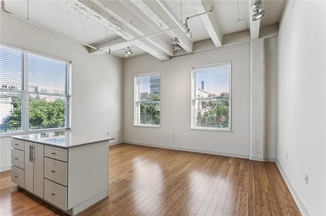 835 Julia St Unit 8, New Orleans, LA 70113 - kitchen featuring beamed ceiling, a kitchen island, and light wood-style floors