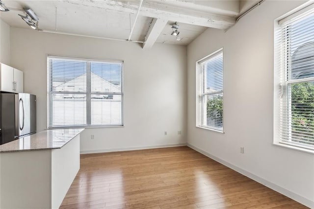 835 Julia St Unit 8, New Orleans, LA 70113 - unfurnished dining area with rail lighting, beam ceiling, and light wood finished floors